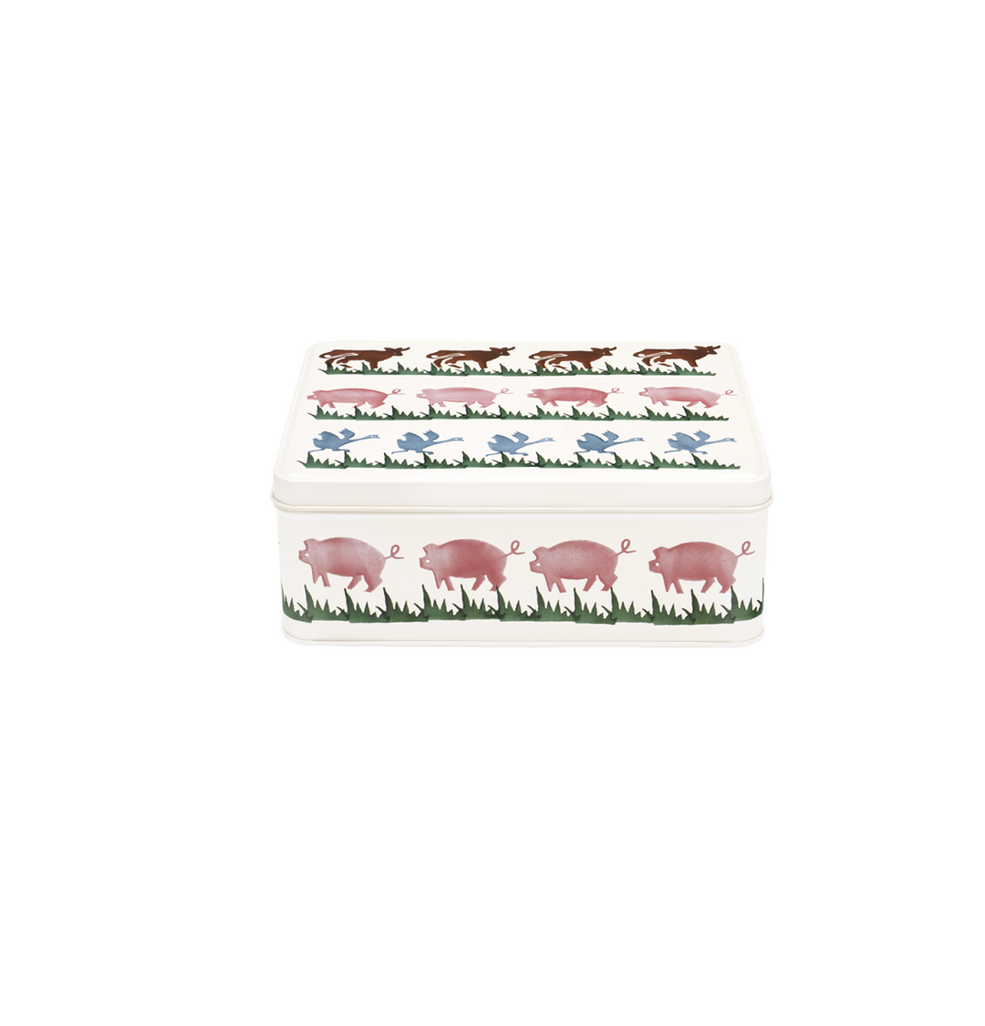 A rectangular metal storage tin with a lid, decorated with a repeating pattern of pink pigs in a grassy field and small blue birds, shown on a plain white background.