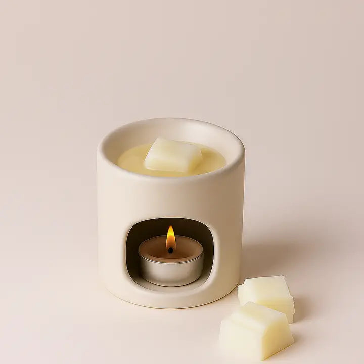 White wax warmer with a lit candle inside on a beige background