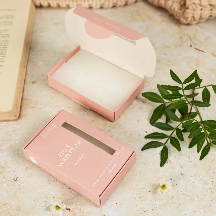 Two boxes of Pintail Fig &amp; Wild Pear Wax Melts on a texture surface with a plant