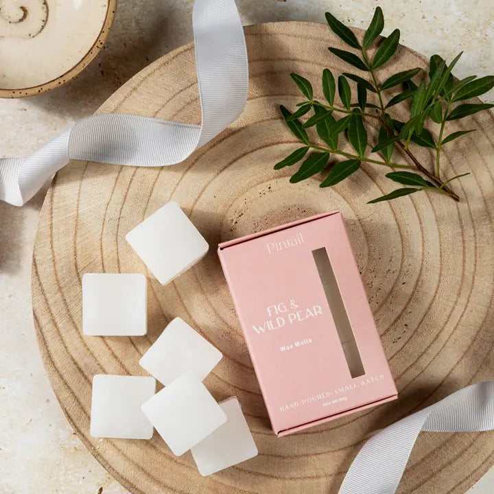 Pink wax melts packaging with white wax melts on a wooden surface
