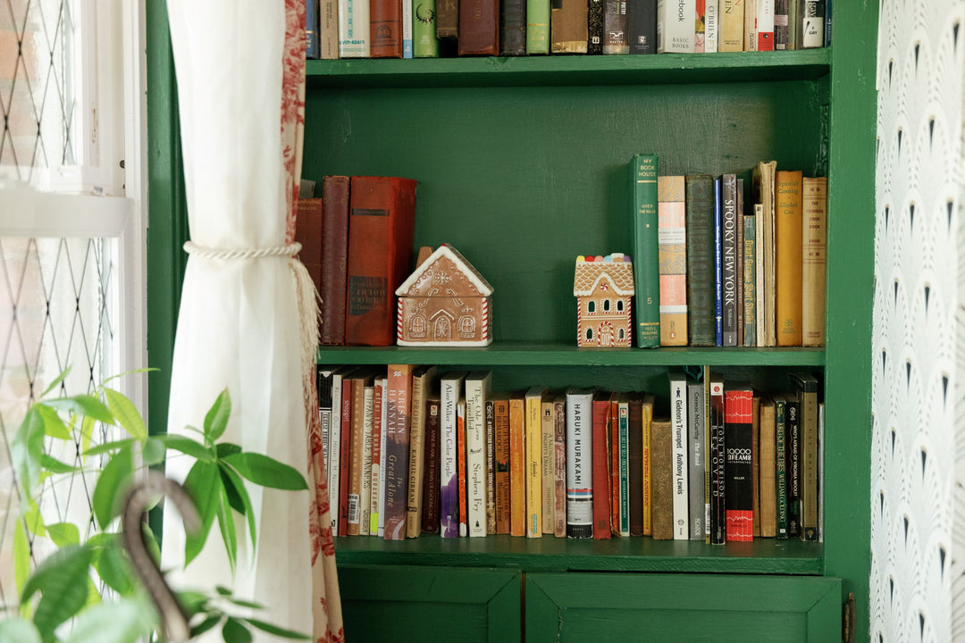 Two gingerbread shaped ornaments on a green bookshelf
