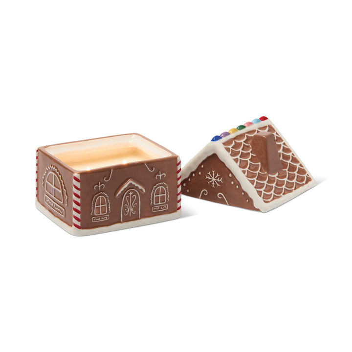 Gingerbread house-shaped container with a candle inside on a white background
