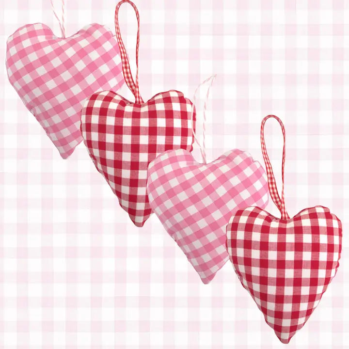 Four heart-shaped fabric hanging ornaments in pink and red gingham checkered patterns, arranged diagonally on a matching pink and white gingham background.