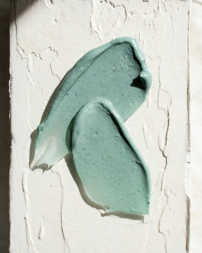 Close-up of a greenish-blue facial mask on a textured white background