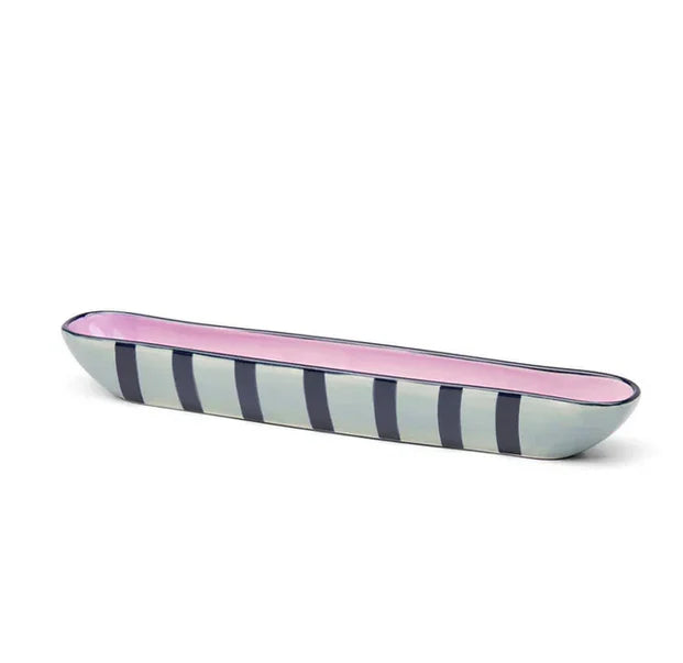 Long, narrow ceramic dish with pink interior and striped exterior on a white background