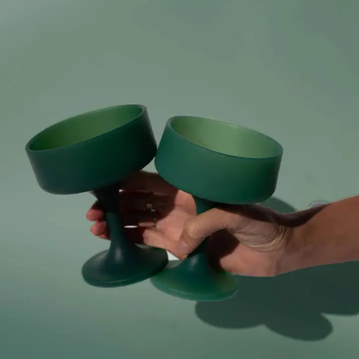 Two matte dark green silicone cocktail glasses held by a person&
