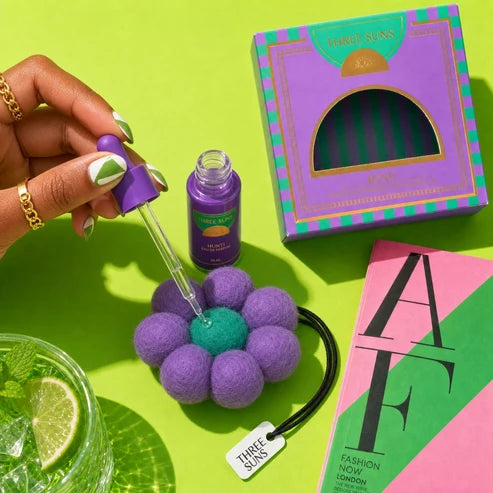 Purple flower-shaped product with a dropper, box, and magazine on a green background
