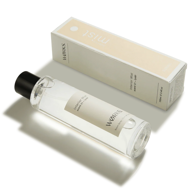 Clear bottle with black cap and beige label next to a beige box labeled &