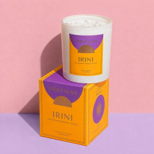 A three suns Irini candle and the box on a pale pink background