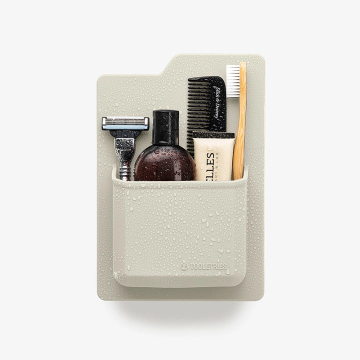 Sand coloured silicone toiletry organiser holding a range of toiletries, on a white background