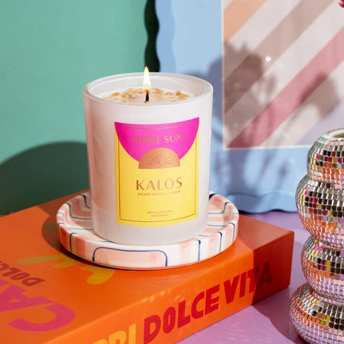 Candle with a colorful label on a decorative coaster, with a disco ball and colorful background.
