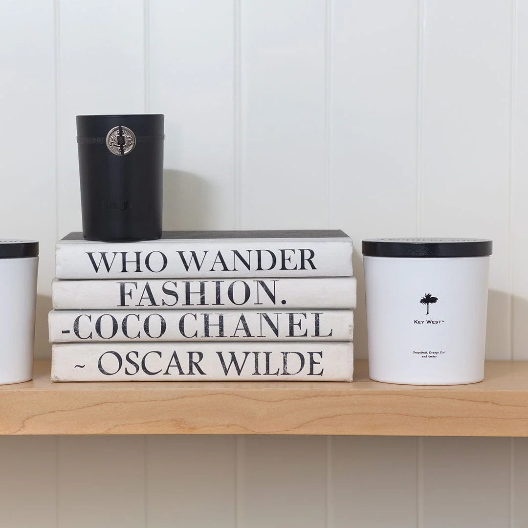 Stack of books with famous quotes on a shelf with decorative containers.