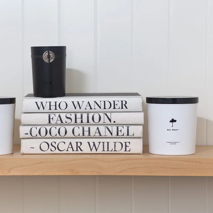Stack of books with famous quotes on a shelf with decorative containers.
