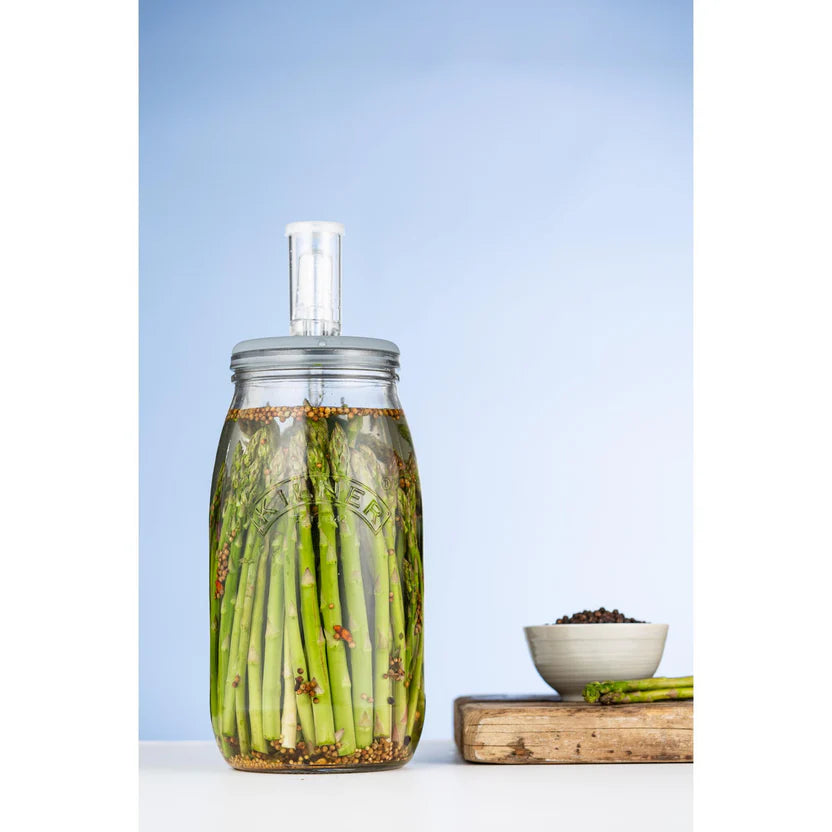 Fermentation jar with asparagus on a light blue background