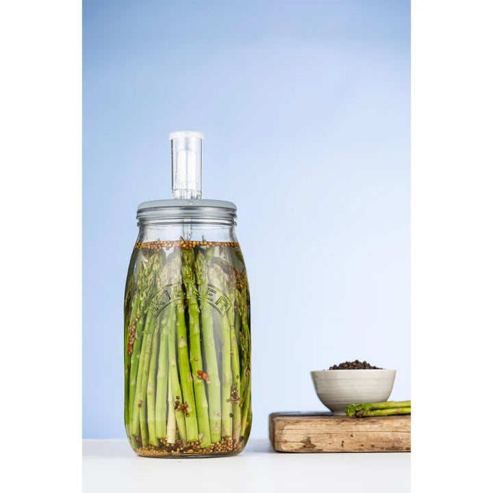 Fermentation jar with asparagus on a light blue background