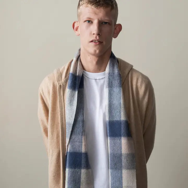 Man wearing a beige cardigan and plaid scarf against a plain background