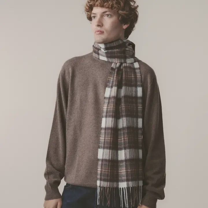 Person wearing a brown sweater and plaid scarf against a plain background