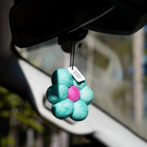 Decorative car air freshener shaped like a flower with a pink center, hanging from a car&