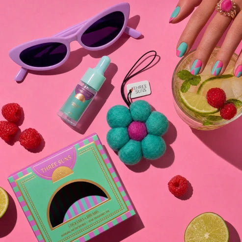 Colorful product display with sunglasses, bottle, flower, and drink on a pink background