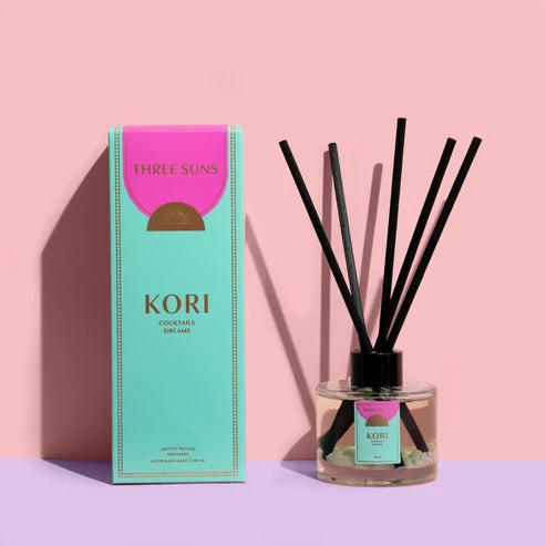 Kori diffuser with black sticks and a pink and green box on a pink background