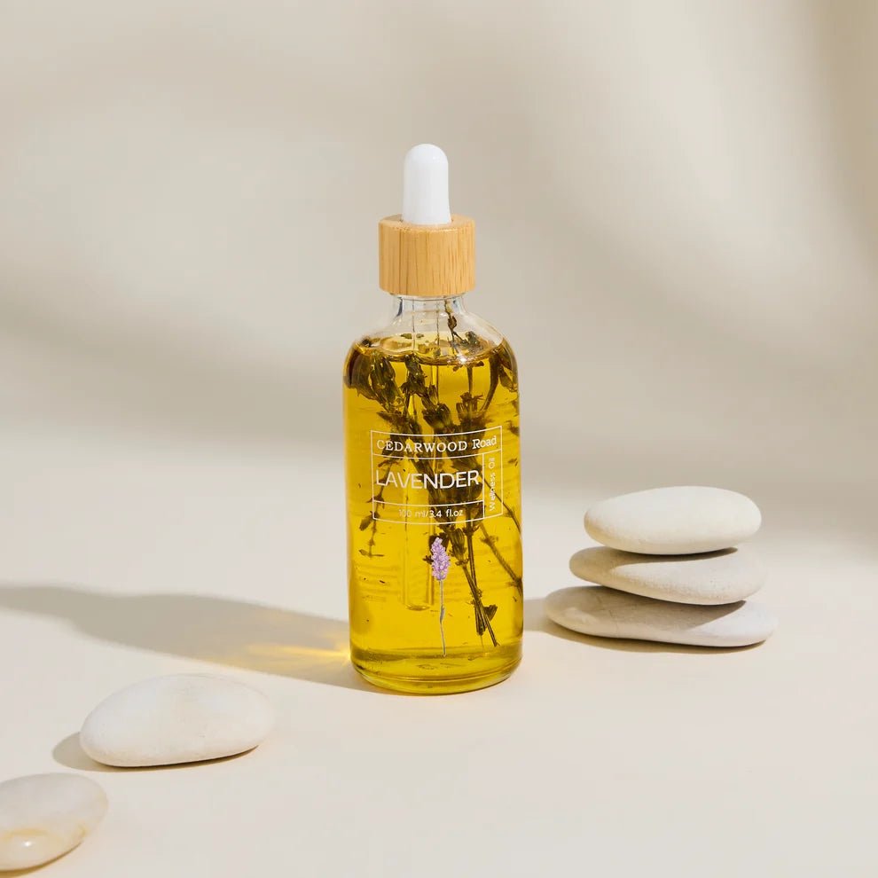 A bottle of Cedarwood Road lavender wellness body oil a beige background with stones near by. 