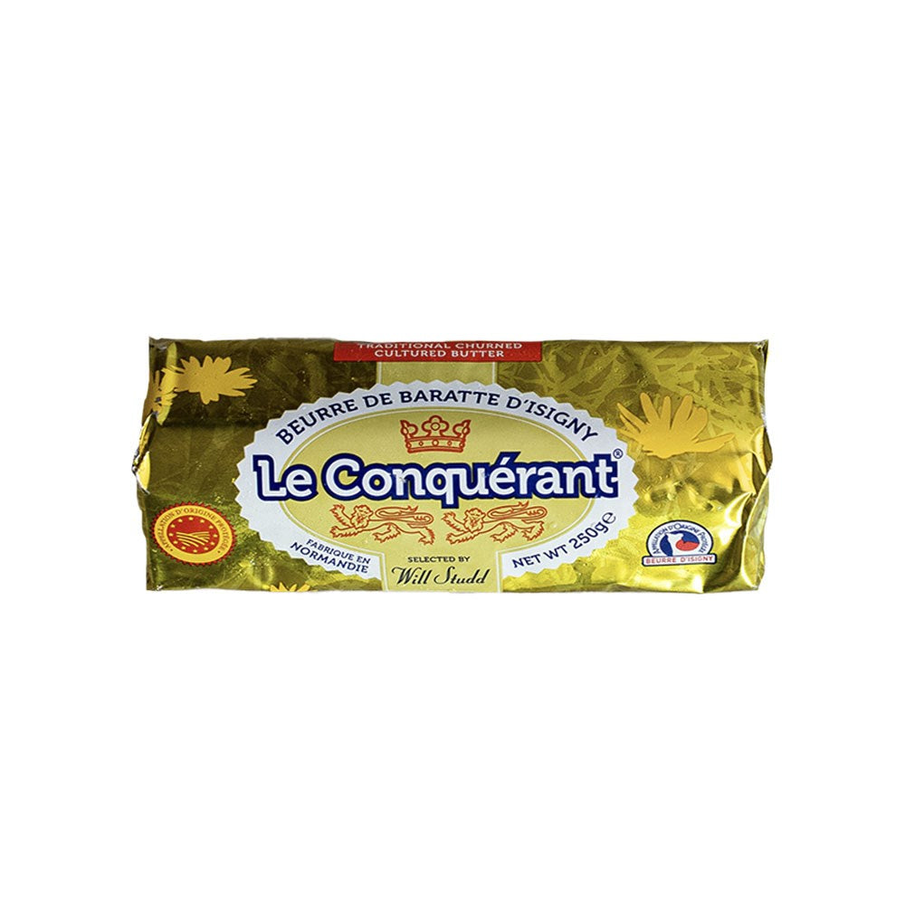 A log of Le Conquerant butter in gold packaging on a white background