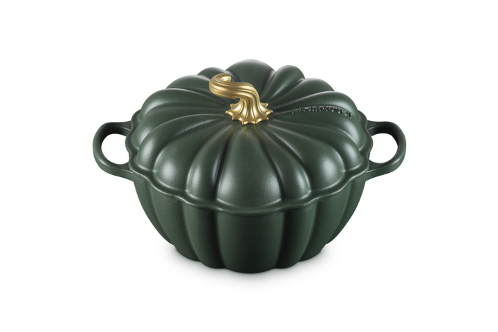 A dark green cast-iron Dutch oven shaped like a pumpkin, featuring a ribbed lid with a metallic gold faux-stem on top and two side handles, shown on a plain white background.