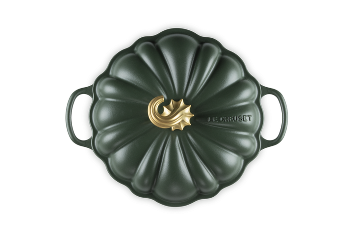 A Le Creuset enameled cast iron Dutch oven with a pumpkin-shaped lid, featuring a dark forest green finish and a gold-toned central logo accent.