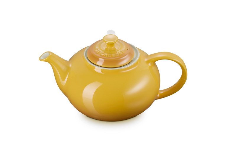 Yellow Le Creuset teapot on a white background