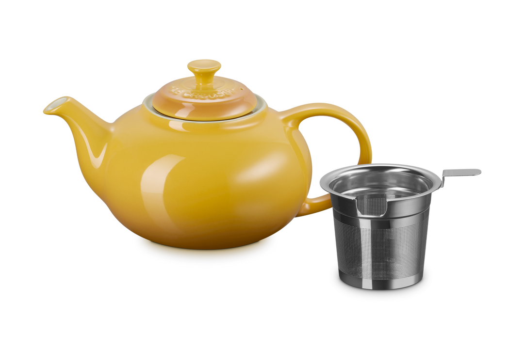 Yellow teapot with a metal infuser on a white background