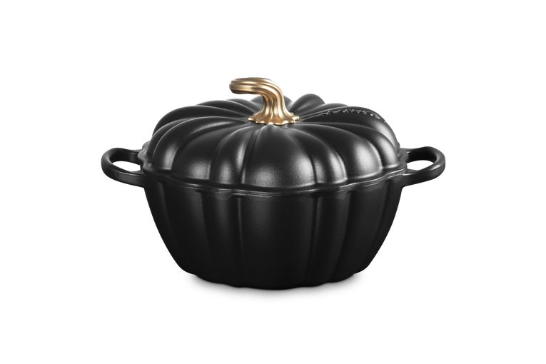 A black cast iron pumpkin-shaped Dutch oven with a lid and a metallic gold handle, shown on a solid white background.