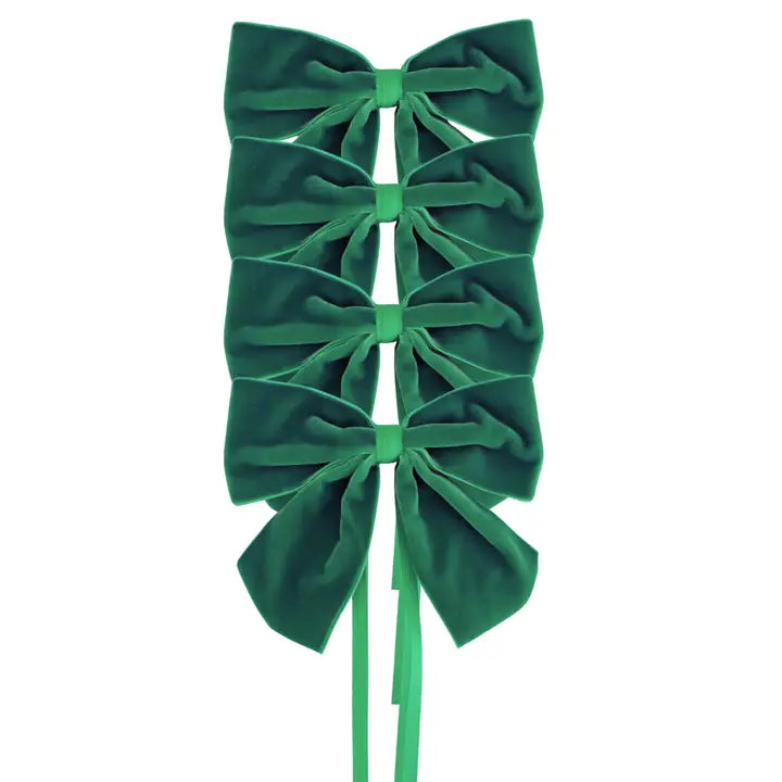 Four green velvet bow napkin holders on white background.