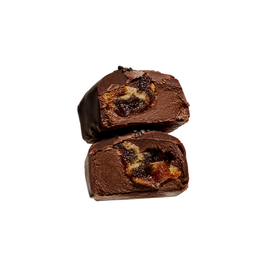 Two halves of a chocolate with a visible filling, stacked on a plain white background.