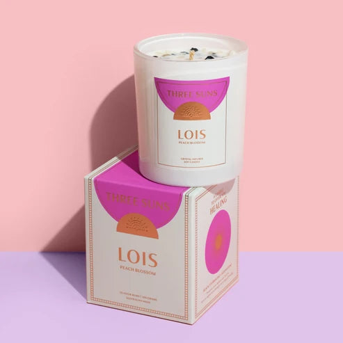 Lois Three Suns Candle with packaging on a pink and purple gradient background