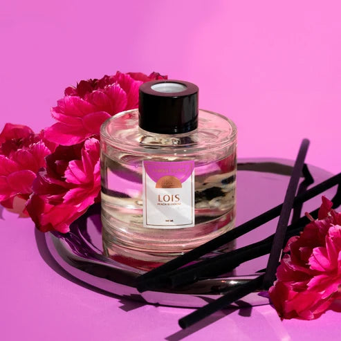 Three Suns Lois reed diffuser near flowers on a pink background