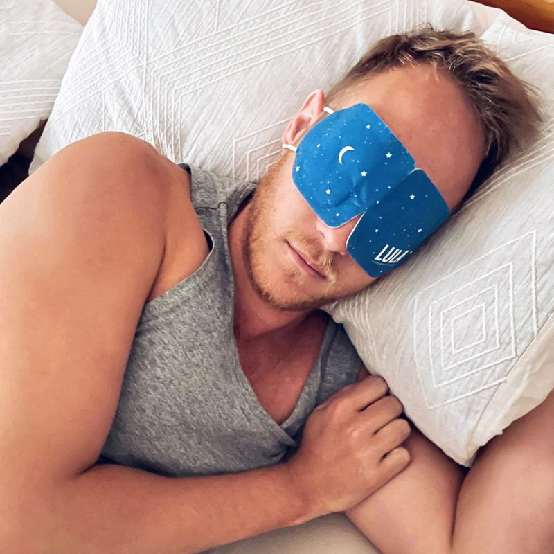 Man lying in bed wearing a blue sleep mask with star pattern