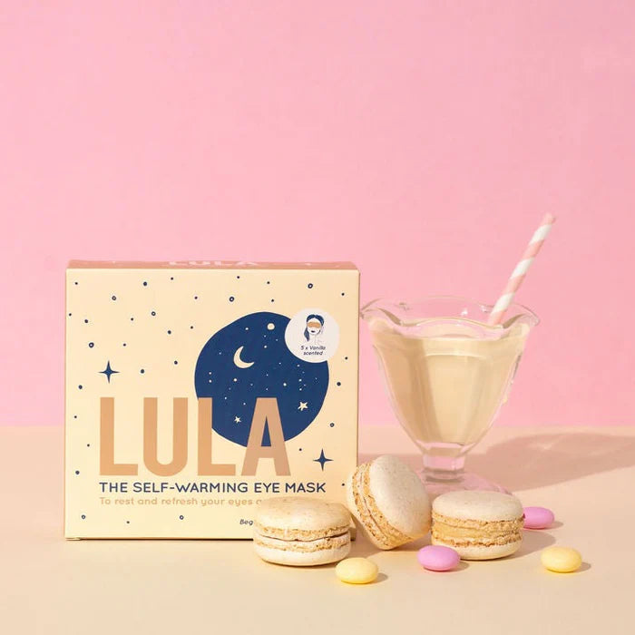 LULA self-warming eye mask packaging with macarons and a smoothie on a pink background