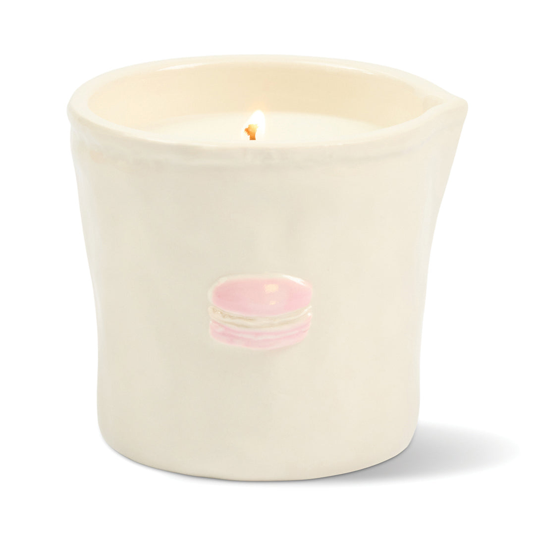 White ceramic candle holder with a lit candle inside on a white background