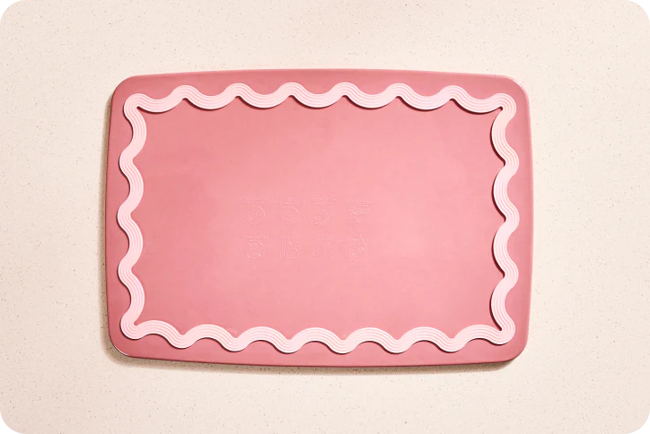 Pink cutting board with wavy edge on a beige background
