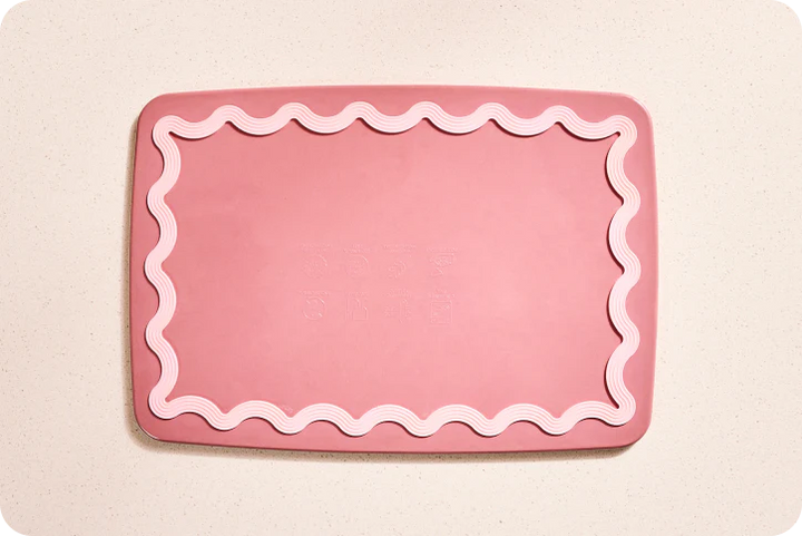 Pink cutting board with wavy edge on a beige background