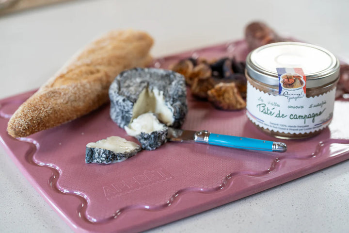 Platter with bread, cheese, and a jar of pâté on a pink platter.