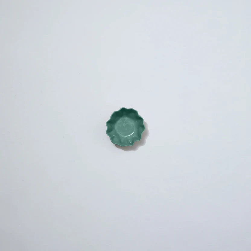Small green ceramic object on a white background