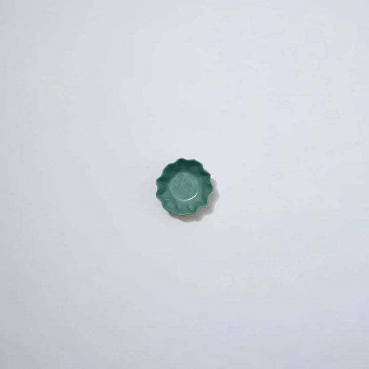 Small green ceramic object on a white background