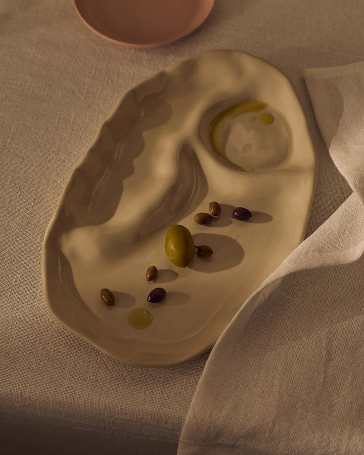 Ceramic dish with olives and oil on a beige surface