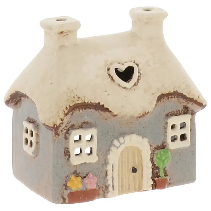 Ceramic house-shaped candle holder with a heart window on a white background