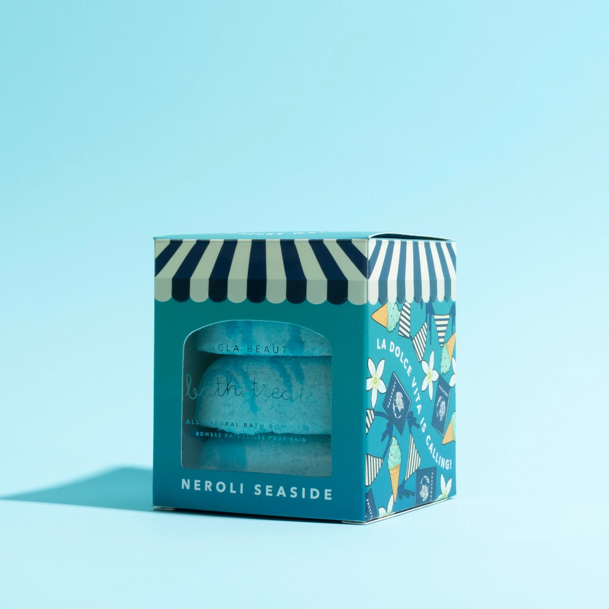 Blue bath bomb in a decorative box with striped design on a light blue background