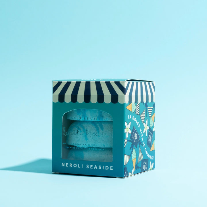 Blue bath bomb in a decorative box with striped design on a light blue background