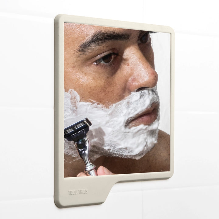 Man shaving in a shower mirror on a white background