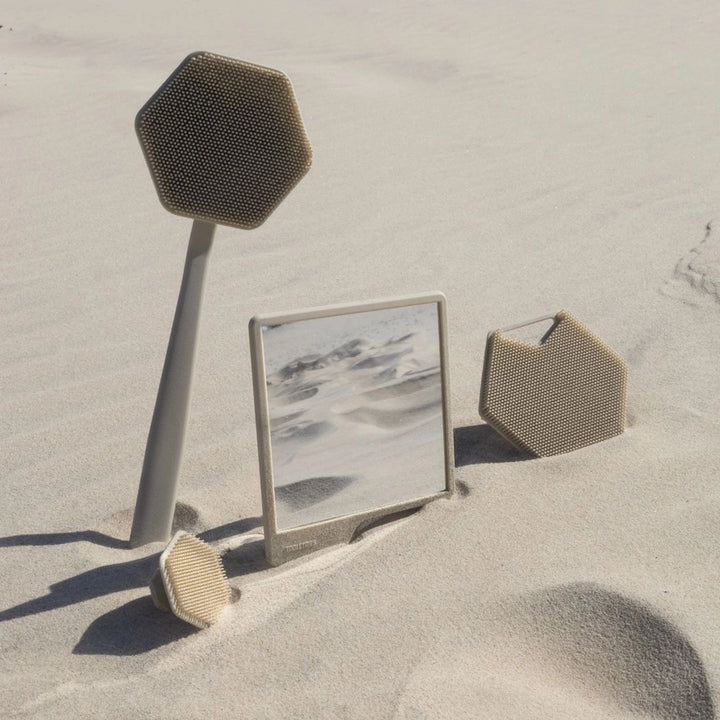 Sand coloured shower accessories arranged in the sand on a beach