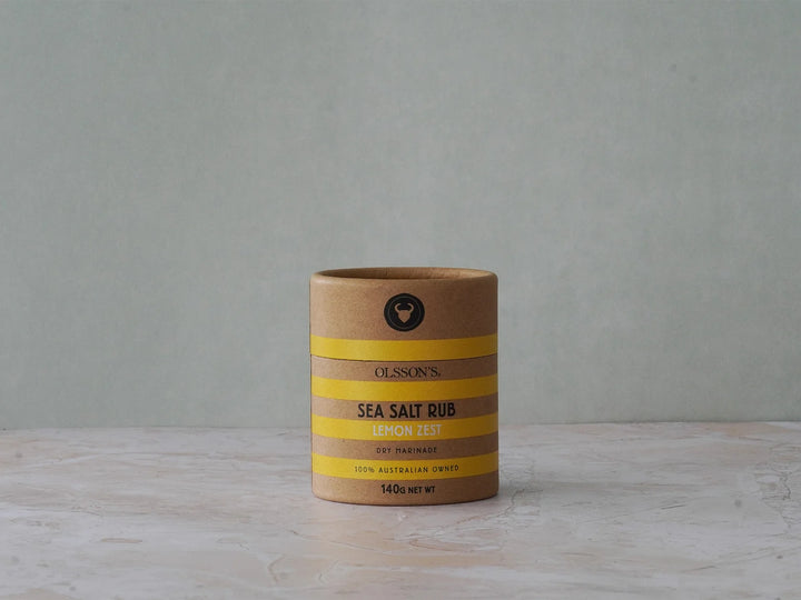Cylindrical container of sea salt rub with striped design on a gray background